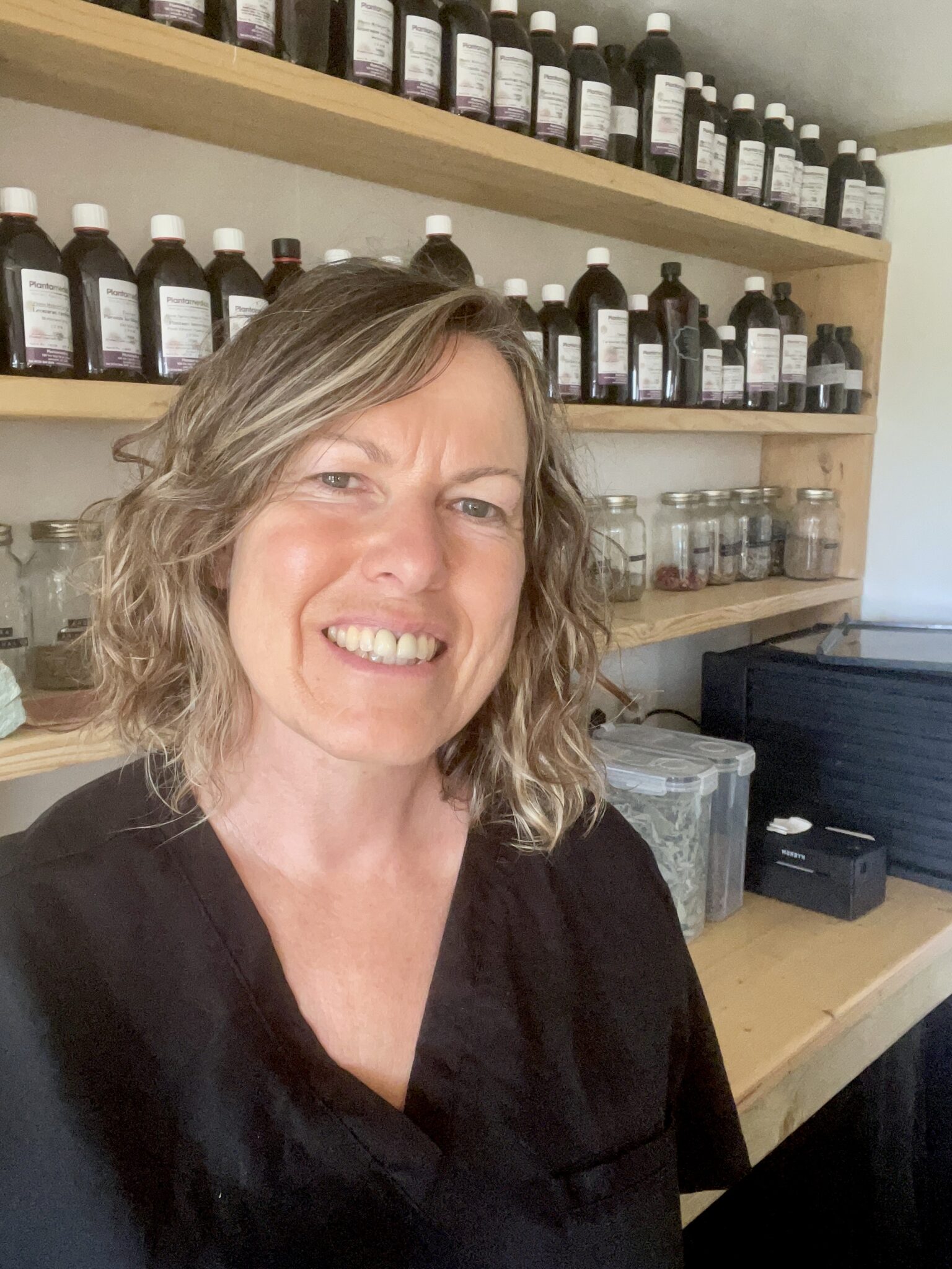 Jules in her practice with shelves of herbal medicine in the background